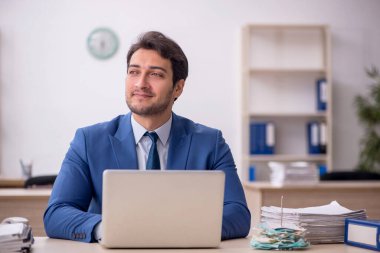 Genç erkek çalışan işyerinde oturuyor.