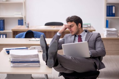 Genç erkek çalışan işyerinde oturuyor.