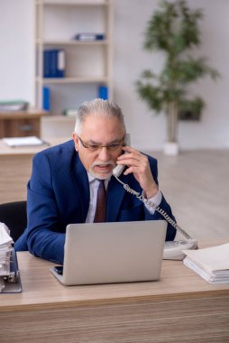 Old employee sitting at workplace