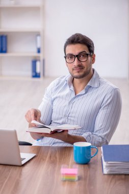 Young businessman employee reading book at workplace