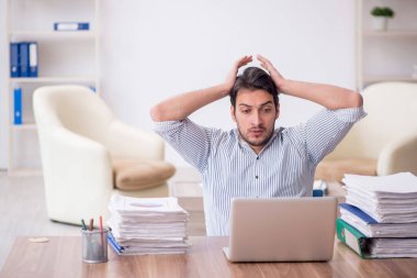 Young employee and too much work at workplace