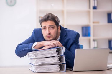 Genç işadamı ve işyerinde çok fazla iş var.