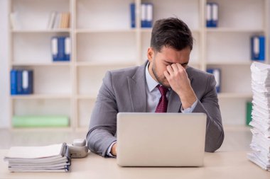 Young employee and too much work at workplace