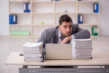 Young employee and too much work at workplace