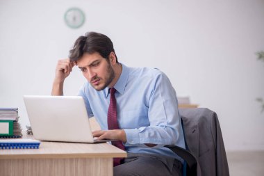 Genç işadamı işyerinde oturuyor.