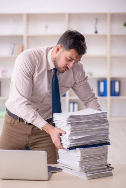 Young employee and too much work at workplace