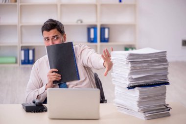 Young employee and too much work at workplace