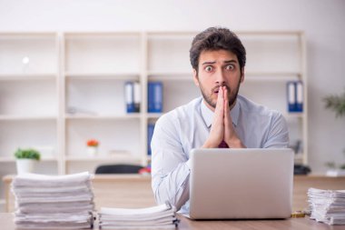 Young employee and too much work at workplace