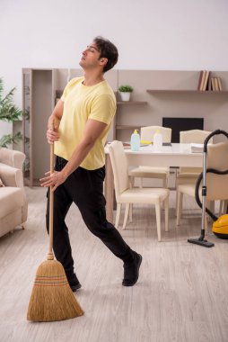 Genç adam evi temizliyor.