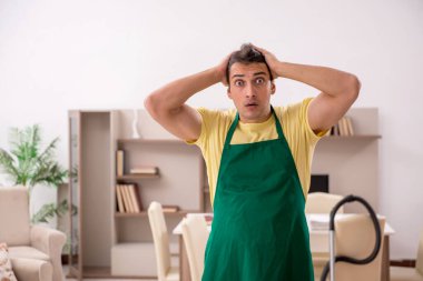 Genç adam evi temizliyor.