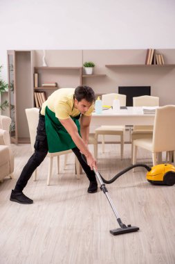 Genç adam evi temizliyor.