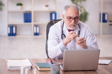 Klinikte çalışan yaşlı bir doktor.