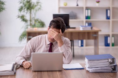 Genç işadamı ve işyerinde çok fazla iş var.