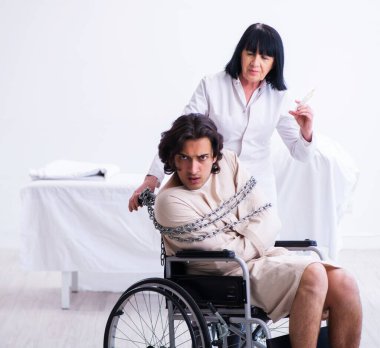 Yaşlı kadın psikiyatrist genç erkek hastayı ziyaret ediyor.