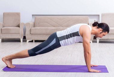 Genç adam evde antrenman ve egzersiz yapıyor.