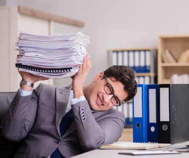 İş adamı kağıt yığınlarıyla boğuşuyor.