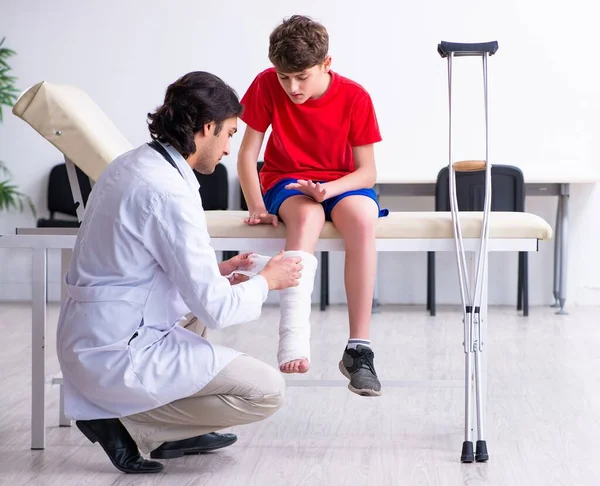 足を負傷した少年は若い医者の外傷科医を訪ねて — ストック写真