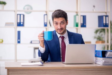 Young employee drinking tea in the office