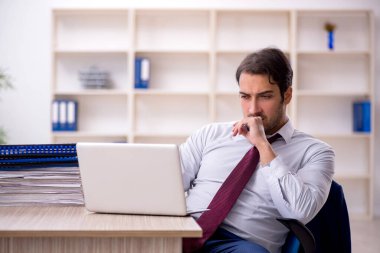 Genç işadamı ve işyerinde çok fazla iş var.