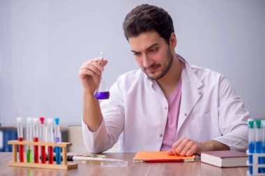 Young chemistry teacher sitting in the classroom