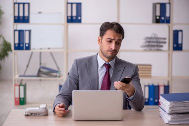 Genç işadamı işyerinde oturuyor.