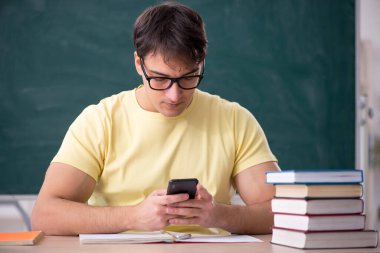 Genç öğrenci yeşil panonun önünde oturuyor.