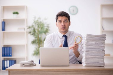 Young auditor holding loupe at workplace
