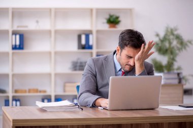 Genç işadamı işyerinde oturuyor.