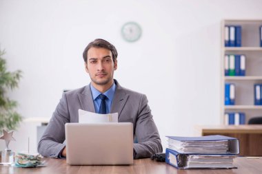 Genç işadamı işyerinde oturuyor.