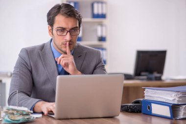 Genç işadamı işyerinde oturuyor.