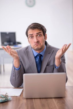 Genç işadamı işyerinde oturuyor.