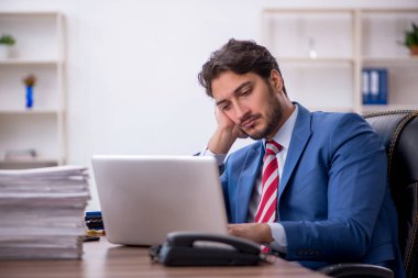 Genç işadamı ve işyerinde çok fazla iş var.