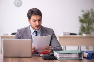 Genç erkek çalışan işyerinde oturuyor.