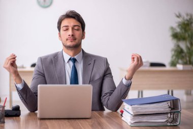 Genç erkek çalışan işyerinde oturuyor.