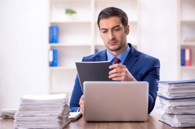 Genç işadamı ve işyerinde çok fazla iş var.