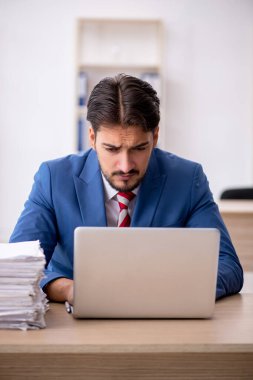 Genç işadamı ve işyerinde çok fazla iş var.