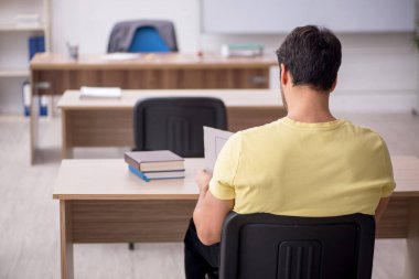 Young student teacher sitting in the classroom