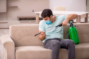 Genç müteahhit evde haşere kontrolü yapıyor.