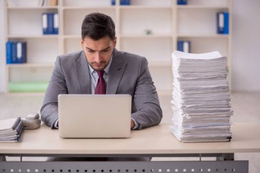 Young employee and too much work at workplace