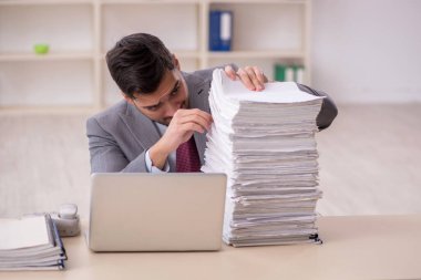 Young employee and too much work at workplace