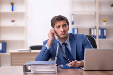 Genç bir erkek işçi ve işyerinde çok fazla iş var.