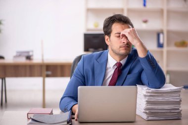 Genç işadamı ve işyerinde çok fazla iş var.