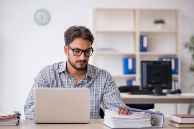 Genç erkek çalışan işyerinde oturuyor.