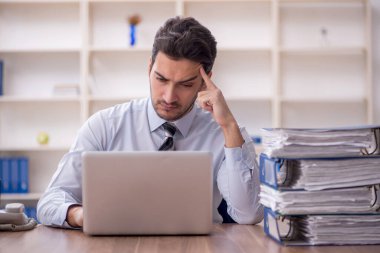 Genç işadamı ve işyerinde çok fazla iş var.