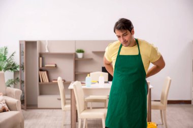 Genç adam evi temizliyor.