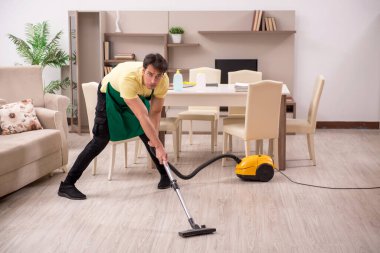 Genç adam evi temizliyor.