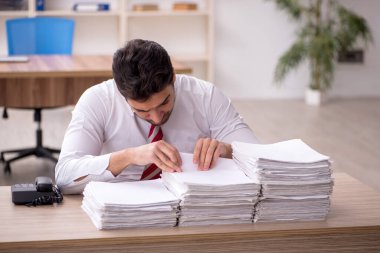 Genç işadamı ve işyerinde çok fazla iş var.