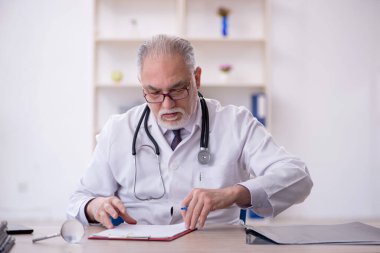 Klinikte çalışan yaşlı bir doktor.