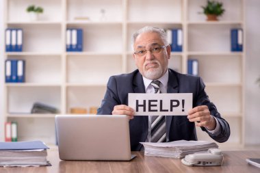 Old businessman employee unhappy with excessive work at workplace