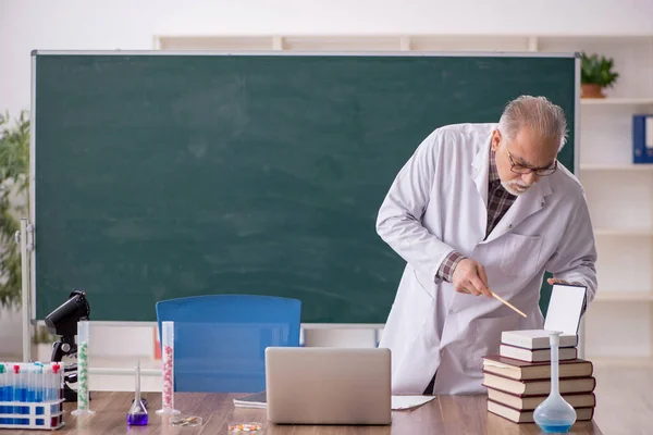 Old teacher chemist sitting in the classroom
